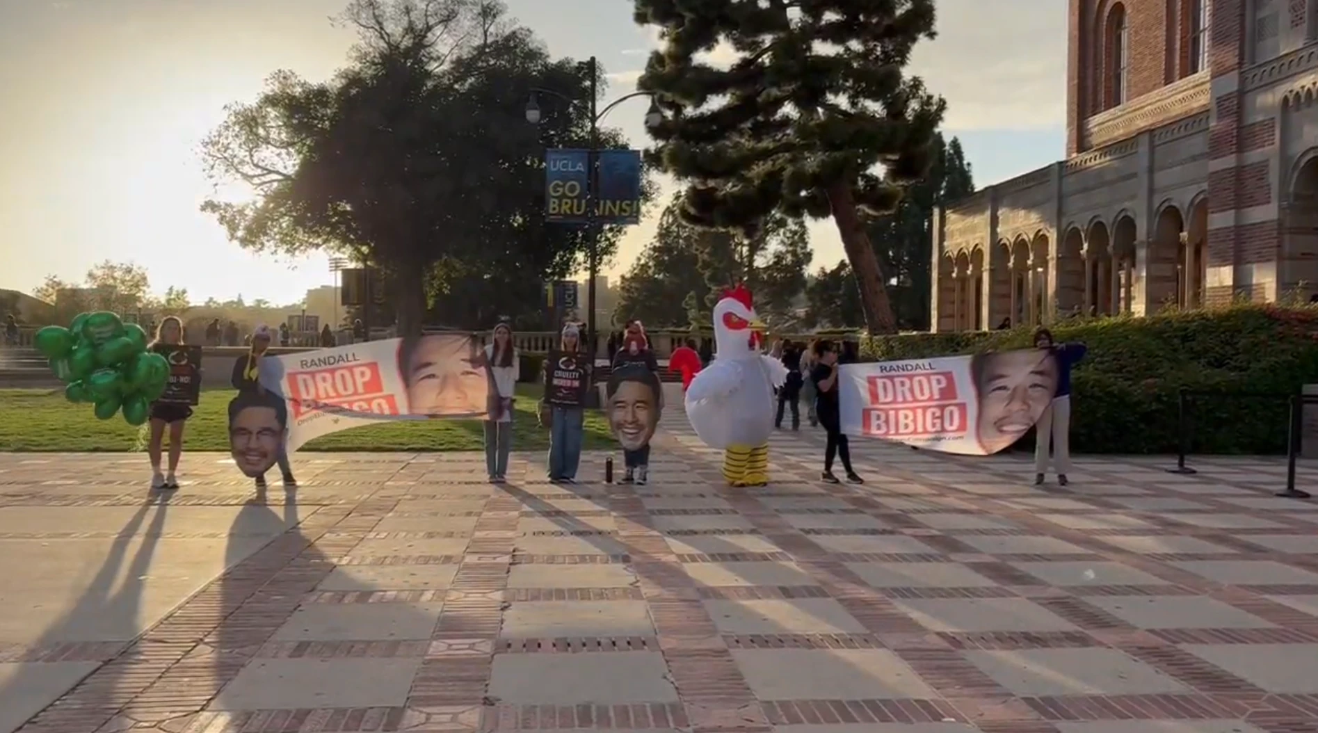 BFAR members holding Drop Bibigo banners outside Royce Hall, with a volunteer in a chicken costume