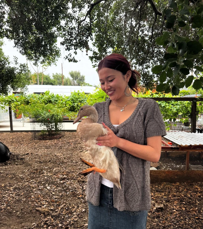A volunteer smiling while holding a duck